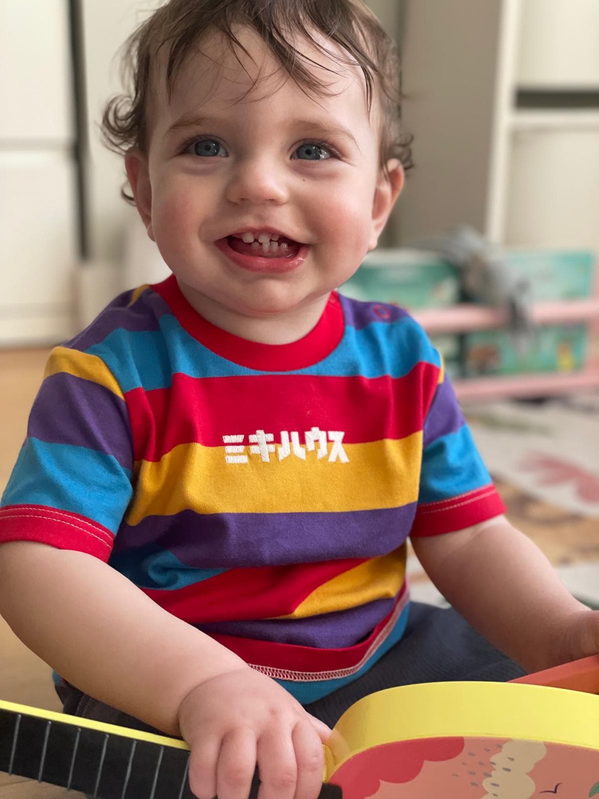 Isaac smiling in a rainbow striped shirt